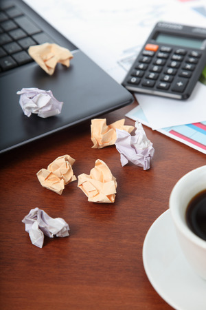 Laptop, calculator, cup of coffee and crumpled paper on the tableの写真素材