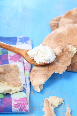 Pita bread and soft cheese on a spoon on a tableの写真素材