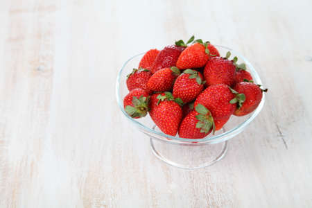 Ripe strawberries in a bowl on a tableの写真素材