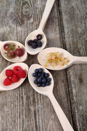 Different ripe berries in a wooden spoons on the tableの写真素材