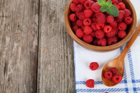 Ripe raspberries in a bowl on a wooden tableの写真素材