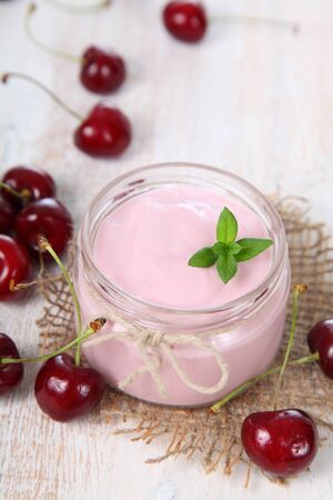 Cherry yogurt and ripe cherry on a wooden table. Summer dessert.の写真素材