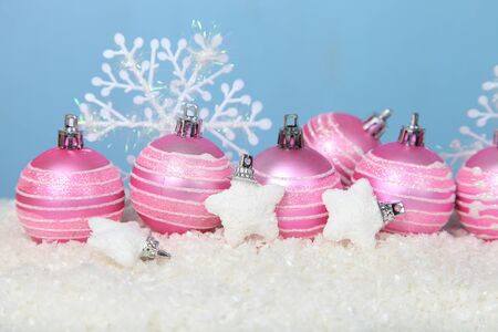 Pink balls and stars in snow on a blue background. Christmas composition.の写真素材