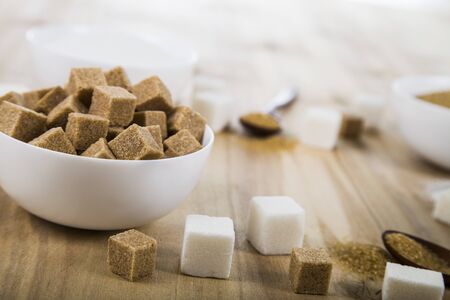 Cane and white sugar in a white bowls on the tableの写真素材