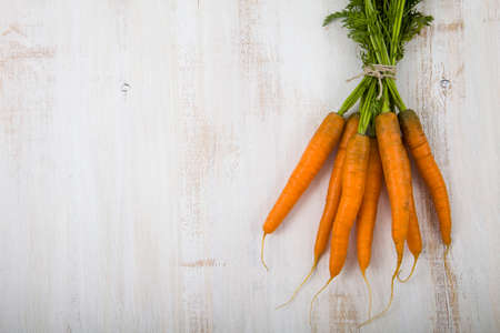 Carrot with leaves on an old wooden tableの写真素材