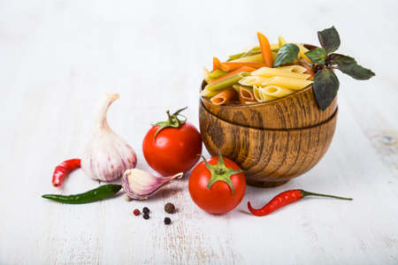 Raw pasta and spices in wooden bowlsの写真素材