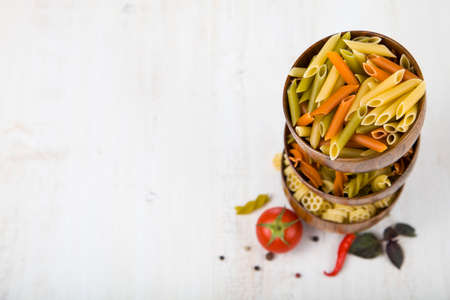 Raw pasta and spices in wooden bowls