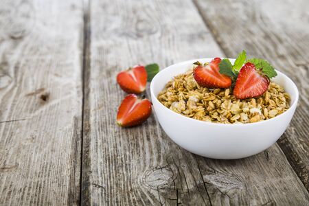 Granola with strawberry on a wooden table. Healthy eating for breakfast.の写真素材