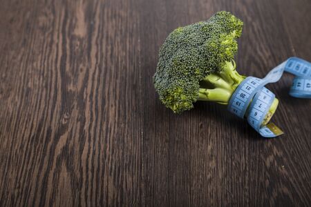 Broccoli and measuring tape on a table close-up. Concept of healthy nutrition and diet.の写真素材