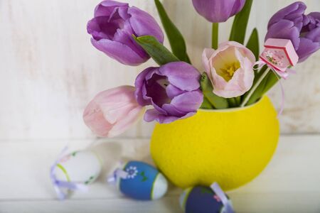 Bouquet purple tulips and Easter eggs on a light wooden table. Easter still life can be used as a postcard.の写真素材