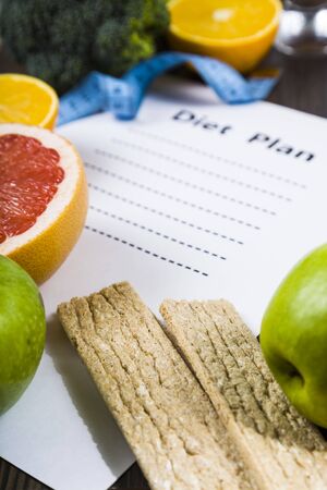 Food and sheet of paper with a diet plan on a dark wooden table. Concept of diet and healthy lifestyle.の写真素材