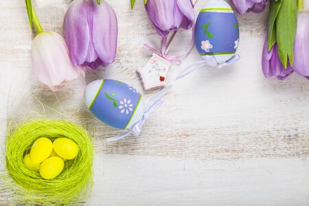 Bouquet purple tulips and Easter eggs on a light wooden table. Easter still life can be used as a...