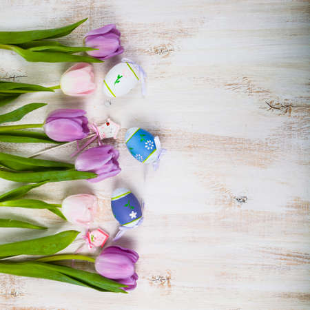 Bouquet purple tulips and Easter eggs on a light wooden table. Easter still life can be used as a postcard.の写真素材