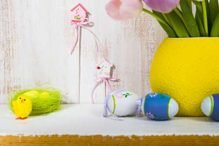Bouquet purple tulips and Easter eggs on a light wooden table. Easter still life can be used as a postcard.の写真素材