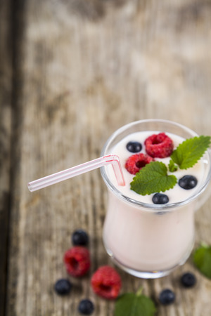 Smoothies or yogurt with fresh berries on a wooden table. Milkshakes with raspberries, blueberries, apricots and mint leaves.の写真素材