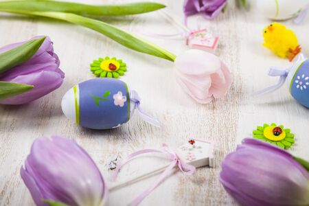 Bouquet purple tulips and Easter eggs on a light wooden table. Easter still life can be used as a...