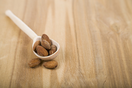 Almonds in a spoon on a wooden table close-up. Tasty and healthy nuts. Top view.の写真素材
