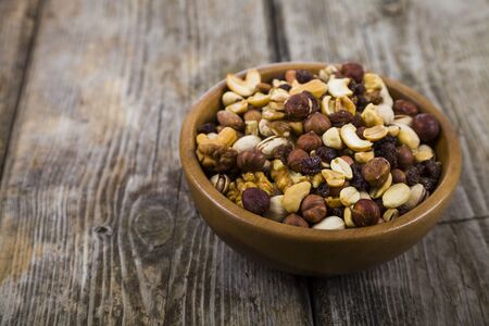 Nuts in a wooden bowl  on a  wooden table. Different kinds of tasty and healthy nuts.