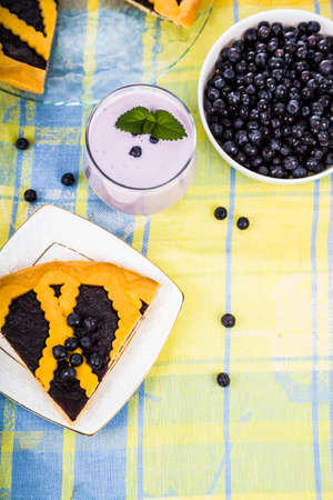 Piece of a blueberry pie and smoothies on a wooden table. Delicious dessert closeup.の写真素材