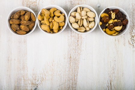 Nuts in a plate on a  wooden table. Different kinds of tasty and healthy nuts.の写真素材