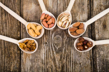 Nuts in a wooden spoons on a  wooden table. Different kinds of tasty and healthy nuts.