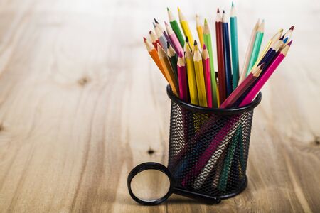 Back to school. Color pencils and magnifier on a wooden table.の写真素材