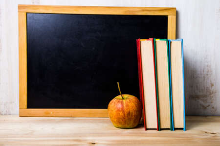 Back to school. Books and an apple on the background of a school boardの写真素材