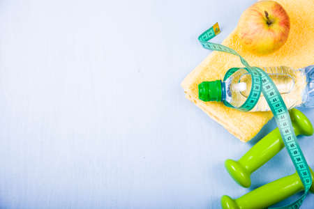 Dumbbells and a bottle of water on a wooden table. Concept of fitness and a healthy lifestyle.の写真素材