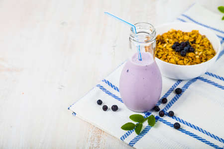 Smoothies,muesli and ripe blueberries on a wooden table. Milk drink with ripe berries, healthy food.の写真素材