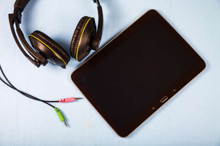 Tablet and headphones on a blue wooden table close-upの写真素材
