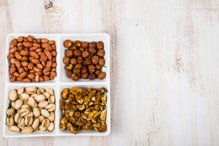 Bowl with nuts on a  wooden table. Different kinds of tasty and healthy nuts. Top viewの写真素材