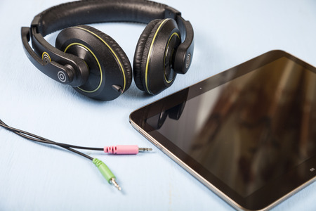 Tablet and headphones on a blue wooden table close-upの写真素材