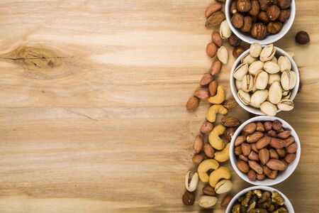 Four bowls with nuts on a  wooden table. Different kinds of tasty and healthy nuts.の写真素材