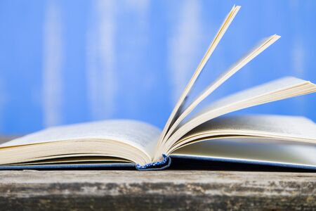 Open book on a wooden table on a blue background.の写真素材