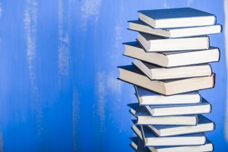 Stack of books on a blue background. A lot of books are close-up.の写真素材