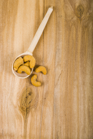 Cashew in a spoon on a wooden table close-up.の写真素材