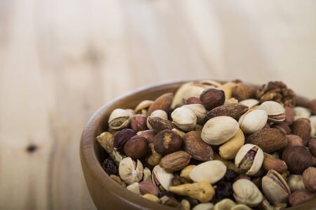 Nuts in a wooden bowl  on a  wooden table. Different kinds of tasty and healthy nuts.
