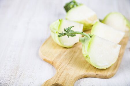 Chopped kohlrabi on chopping board on a wooden table.の写真素材