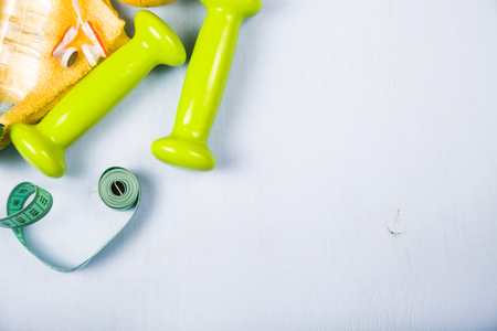 Dumbbells, an apple, a towel and a bottle of water on a blue wooden table. Concept of fitness and a healthy lifestyle.の写真素材