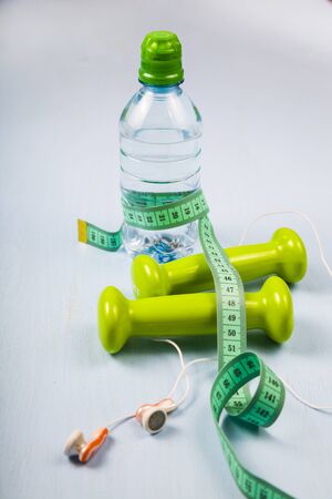 Dumbbells and a bottle of water on a blue wooden table. Concept of fitness and a healthy lifestyle.の写真素材
