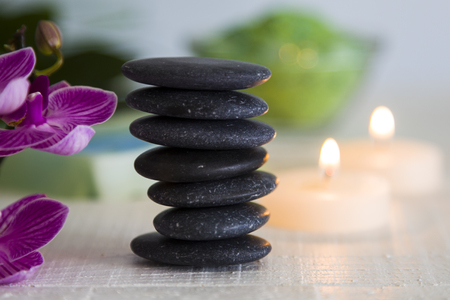 Spa treatments on wooden table. Sea salt, spa stones, orchid and burning candles.の写真素材