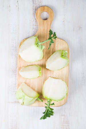 Chopped kohlrabi on chopping board on a wooden table. Delicious cabbage close-up, healthy eating.の写真素材