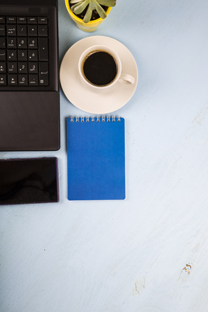 Workplace of  businessman with a laptop, top view. On the table are coffee, laptop, phone and plantの写真素材