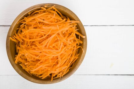 Grate  carrots in a bowl on a wooden table, top view .Tasty and healthy food. Diet.の写真素材