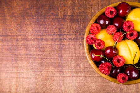 Ripe berries in a plate on a wooden table. Delicious and healthy dessert close-up, healthy diet.の写真素材