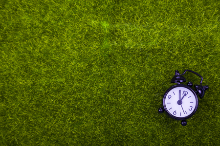 Alarm clock on green grass close-upの写真素材