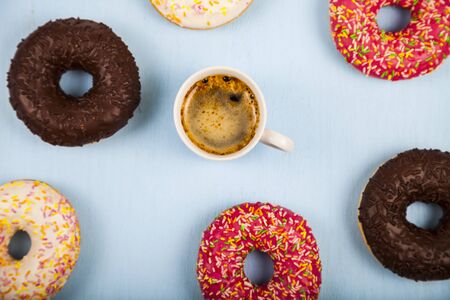 Donuts and a cup of coffee close-up on a blue wooden background.Tasty breakfast.Top view.の写真素材