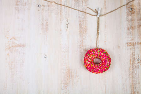 Pink donut on a rope on a wooden background. Delicious and sweet dessert.の写真素材