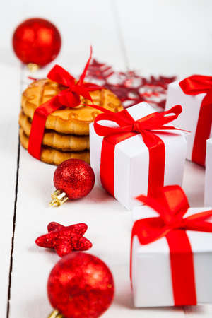Christmas cookie with a red bow, spruce branch, gift and balls. Beautiful still life on a wooden table.の写真素材