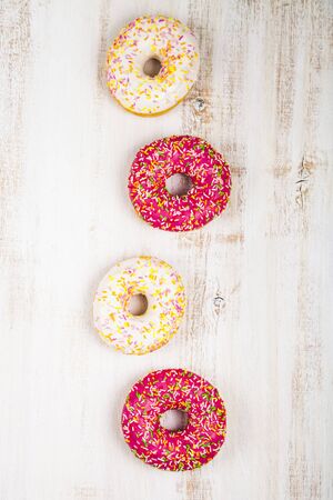 Multicolored donuts close-up on a wooden background. Delicious dessert.の写真素材